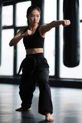 woman in black outfit practicing martial moves with punching bag