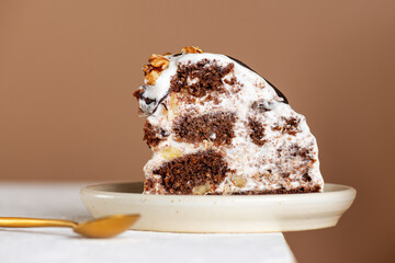 Piece of Pancho cake with pineapple and sour cream topped with chocolate biscuit, walnut and spoon on the edge of the table. Vegan dessert. Sugar, lactose and gluten free.