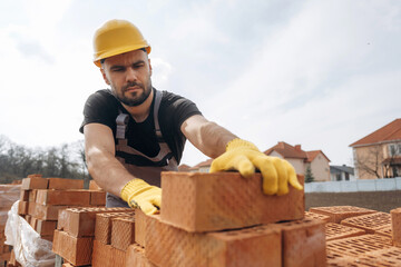 Work in progress. Construction man is at job with bricks outdoors