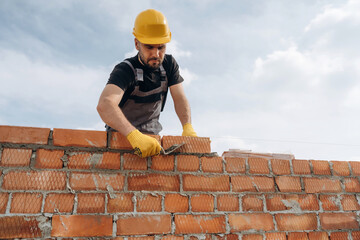 Work in progress. Construction man is at job with bricks outdoors