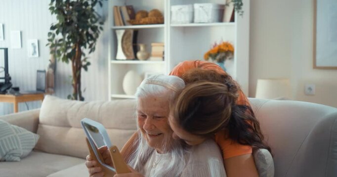 Cheerful, mature daughter hugs her old, happy mother after combing her hair and giving her beauty care at home.
