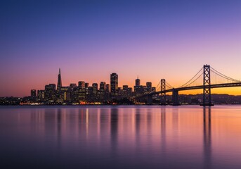 Naklejka premium San Francisco skyline at dusk with the Bay Bridge and beautiful sunset colors over the water.