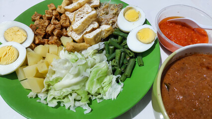 Gado-gado is a mixed vegetables salad with peanud sauce often also including boiled eggs, boiled potatoes, fried tofu  fried tempeh, and lontong