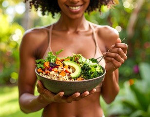Smiling woman holding a fresh vibrant salad bowl outdoors. Features avocado, quinoa, and greens. A sunny image portraying healthy eating and wellness