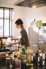 Housewife standing in modern cozy kitchen wipes table surface with microfiber rag, use professional cleaning products for home perfect tidiness, housekeeping concept. Brunette woman cook and cleaning.