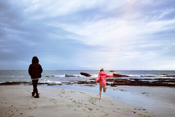 Deux enfants jouant sur des rochers au bord de la mer par temps venteux