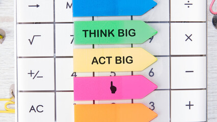 THINK BIG ACT BIG concept words motivating messages are placed on the calculator on bright stickers