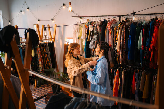 A trendy boutique where friends happily try on outfits and enjoy stylish apparel