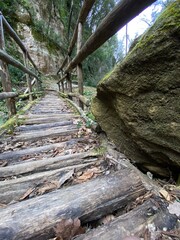 Obraz premium Low angle view of rustic wooden stairs and handrail ascending a steep and rocky path in a natural setting in Serramonacesca, Italy