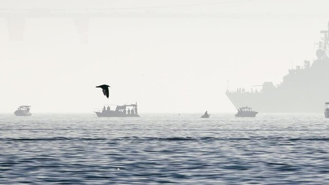 A Turkish Navy destroyer passes by in the Bosphorus, behind some fishing boats, on a foggy day in the Istanbul strait.