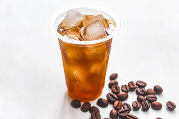 iced coffee in a plastic cup with coffee beans isolated on a white background