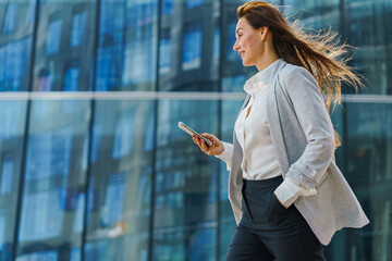 Walking confidently through a modern urban landscape with a smartphone in hand and purpose in stride