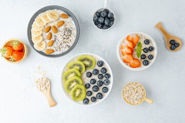 Oatmeal breakfast bowls with fruits and grains on white surface