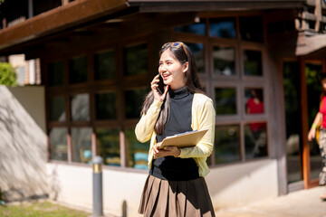 Fototapeta premium A woman is talking on her cell phone while holding a clipboard