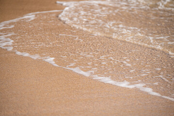 Texture of wet sand and transparent ocean waves, summer concept background