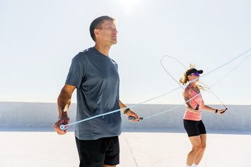 Group of friends engaging in jump rope workout on a sunny rooftop in the early morning