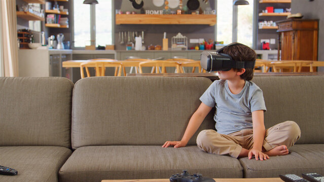 Boy Sitting On Sofa At Home Wearing Virtual Reality Headset