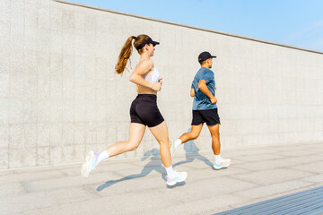 Fitness enthusiasts enjoy a vibrant jog in a modern urban setting under a clear blue sky at midday
