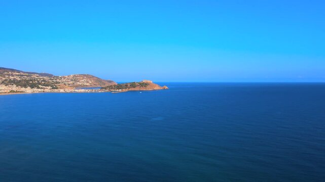 A beautiful view of the ocean with blue skies and mountains in the distance. It's a clear day providing excellent views from a boat or a coastal area.