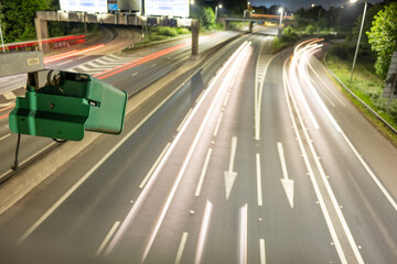 ANPR vehicle surveillance. An ANPR camera on the motorway monitoring traffic flows and speed at night. Light trails of passsing vehicles can be seen,. 