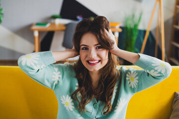Cute woman with brunette hair in casual cardigan smiling happily indoors in a cozy living room...