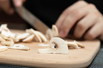 Cooking a dish of mushrooms champignons. Cut vegetables with a knife