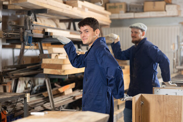 Young male carpenters doing exercises during work process in wood workshop