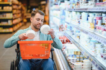 Customer in wheelchair choosing groceries in supermarket dairy section