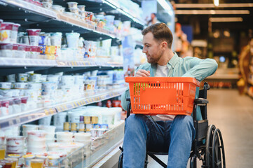 Obraz premium Customer using wheelchair choosing groceries in supermarket dairy section
