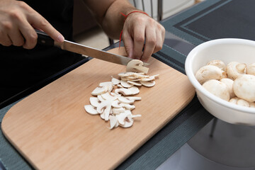 Cooking a dish of mushrooms champignons. Cut vegetables with a knife