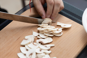 Cooking a dish of mushrooms champignons. Cut vegetables with a knife