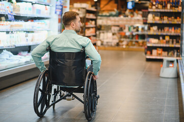 Obraz premium Customer using wheelchair choosing products in supermarket