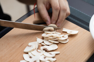 Cooking a dish of mushrooms champignons. Cut vegetables with a knife