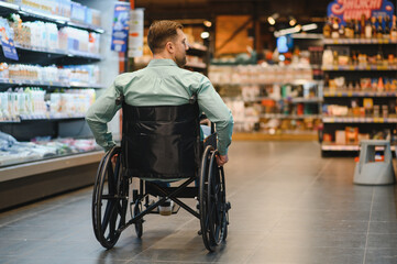 Obraz premium Customer with disability shopping for groceries in wheelchair at supermarket