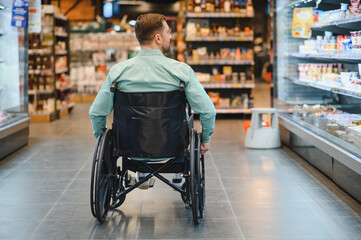 Obraz premium Customer using wheelchair choosing groceries in supermarket