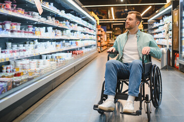 Obraz premium Customer using wheelchair choosing products in supermarket dairy section