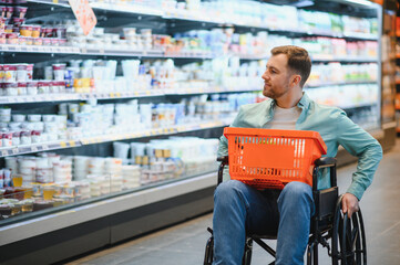 Customer using wheelchair choosing groceries in supermarket dairy section