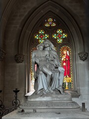 Montju&iuml;c Cemetery in Barcelona at sunset, with dramatic lighting casting long shadows over historic tombstones, crosses, and monuments. A serene yet haunting scene filled with history and symbolism.