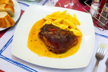 Fried pork with potatoes on a ceramic plate cooked in a restaurant