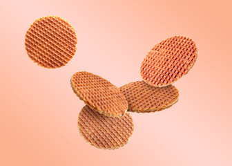 Yummy Dutch waffles (stroopwafels) flying on pink beige gradient background