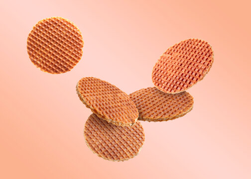Yummy Dutch waffles (stroopwafels) flying on pink beige gradient background