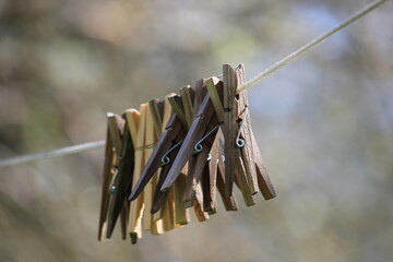 A set of wooden clothespins hanging outside on a string.