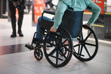 Customer in wheelchair moving through shopping center corridor