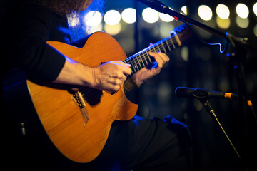Obraz premium Musician playing acoustic guitar on stage during live performance