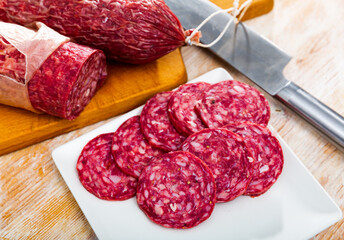 Appetizing Spanish smoked Salchichon sausage, cut into pieces and lying on the table. High quality image..