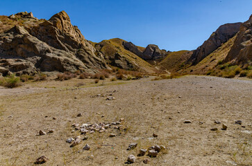Massive Rock Formation in Dry Mountain Valley under Clear Deep Blue Sky with Sparse Vegetation