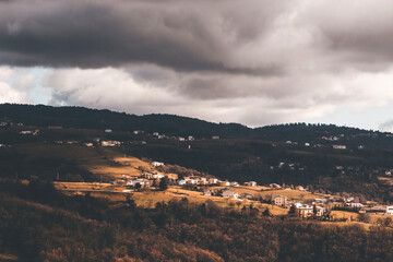 Naklejka premium moody panorama of the small town in lessinia, in italian alps, with dark clouds in the sky