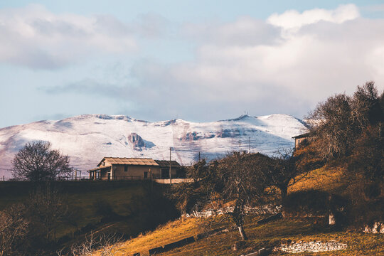 mountain landscape of lessinia in the morning, with snowy mountains in tha background and a stone hut