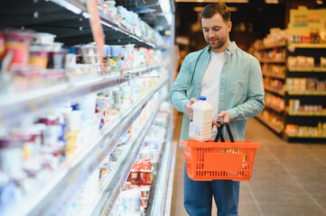 Customer choosing milk bottle in dairy products section of supermarket