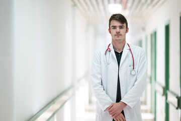 Doctor Standing in Hospital Hallway.Young male doctor standing confidently in a hospital corridor with a stethoscope. Medical professionalism concept.